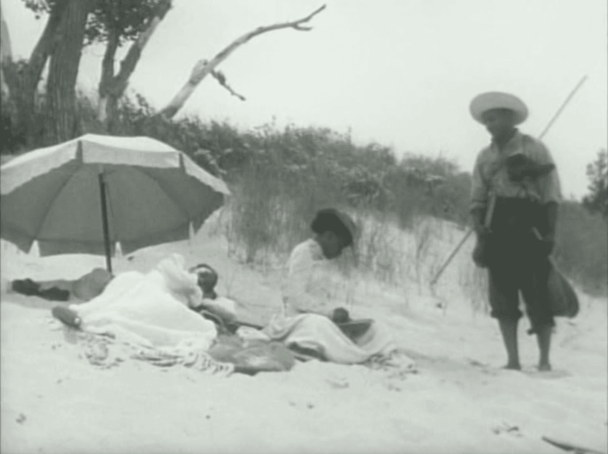 2. This still is from the same film, and is another moment in the same scene. The same woman is now writing on a block with chalk, the man gazes over at what she is writing on this block.