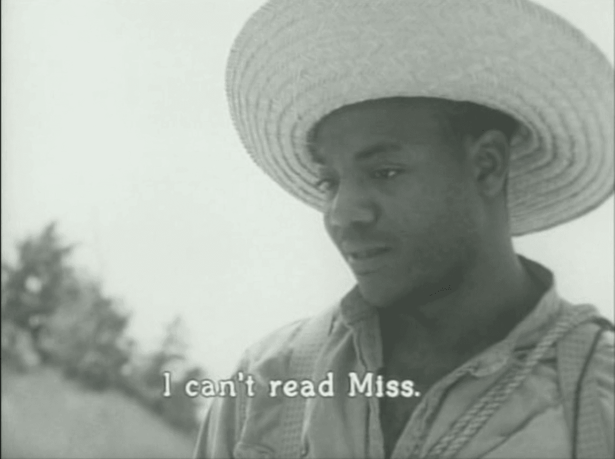 5. Coming back to the beach scene, we see the man’s face up close. He is wearing a hat and many ropes and bags. The captions on the screen state “I can’t read Miss.”.